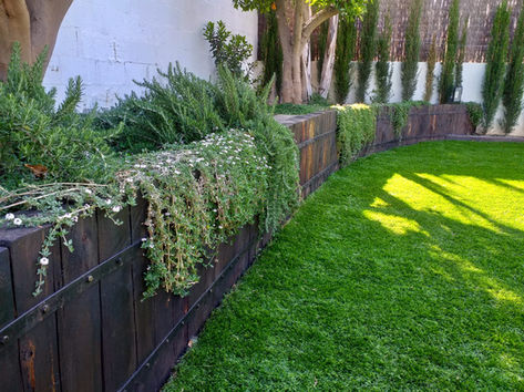 Jardinera feta amb travesses de tren verticals i gespa artificial.