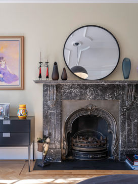 Elegant living room corner at Kingswood Avenue, Queen's Park, featuring a grand marble fireplace with decorative surround and a large round mirror above the mantelpiece