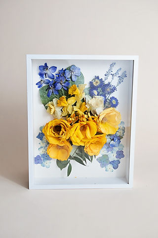 Floral frame art with yellow roses and blue flowers on display.