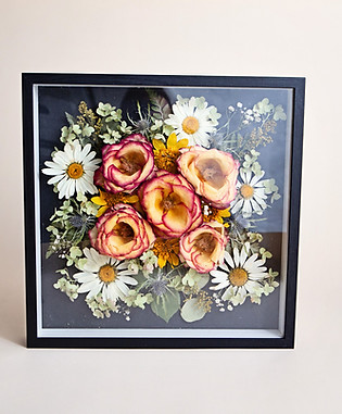 Floral arrangement in a shadow box, featuring roses, daisies, and greenery.