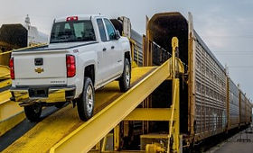 A white truck parked on a ramp, ready for car shipping in Airdrie via an enclosed train transport.