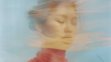 Mulher de olhos fechados, com expressão de cansaço emocional e sensação de atravessamento.