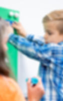 Boy decorating green board with teacher