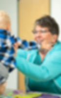 Smiling woman gently interacts with a baby