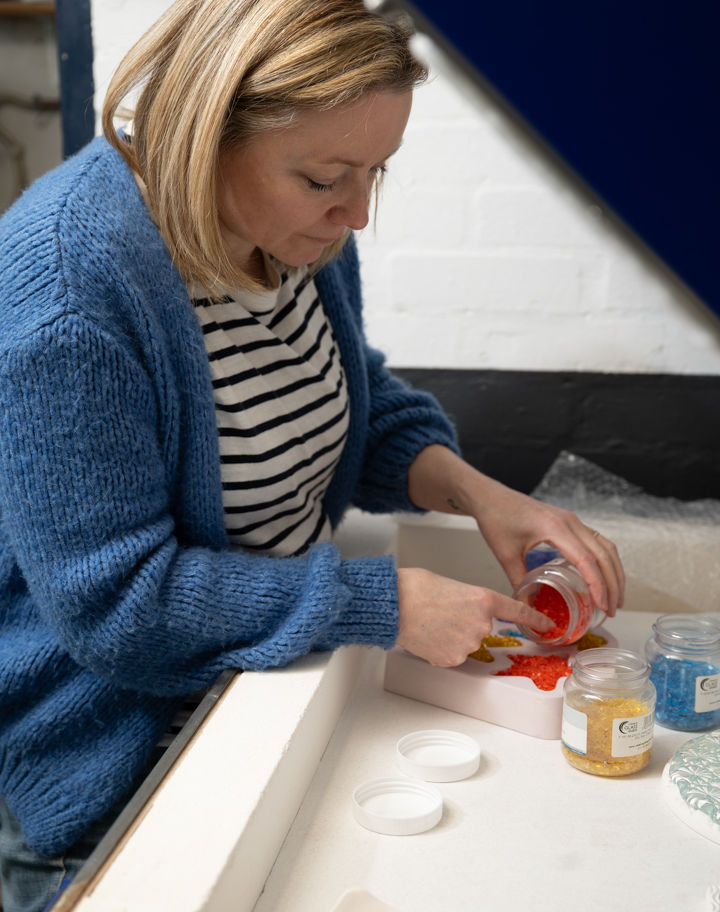 Woman working with colorful paint containers at a table carefully painting.