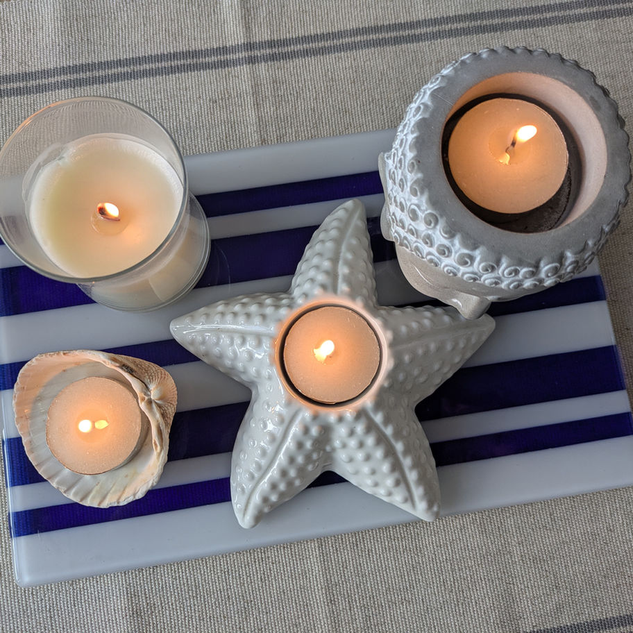 Candles in white starfish and shell holders on a striped background