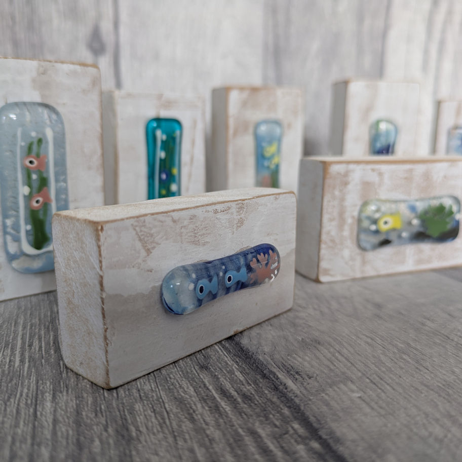 Glass art pieces in white wooden blocks display. Tam's Glass design.