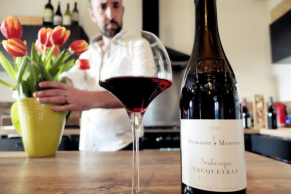 Photo de la cuvée Arabesque. Dans le fond, Nicolas Bria regarde la bouteille en tenant des fleurs