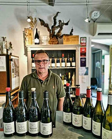 On y voit Laurent Brusset dans son domaine, derrière le comptoir de dégustation. Sur le comptoir, il y a toutes ses cuvées.