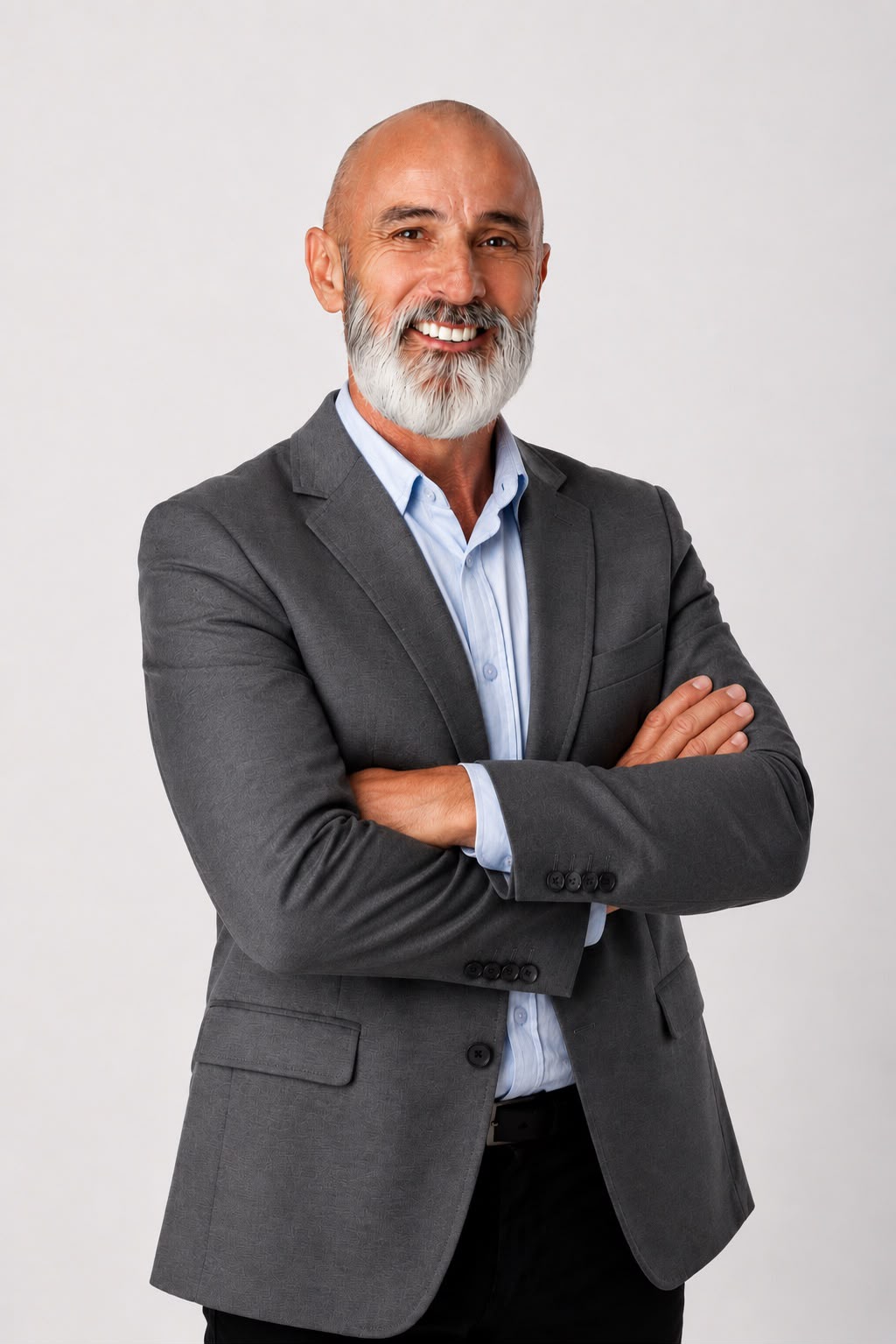 Ricardo Rodrigues, gestor maduro de terno cinza, sorrindo de braços cruzados.