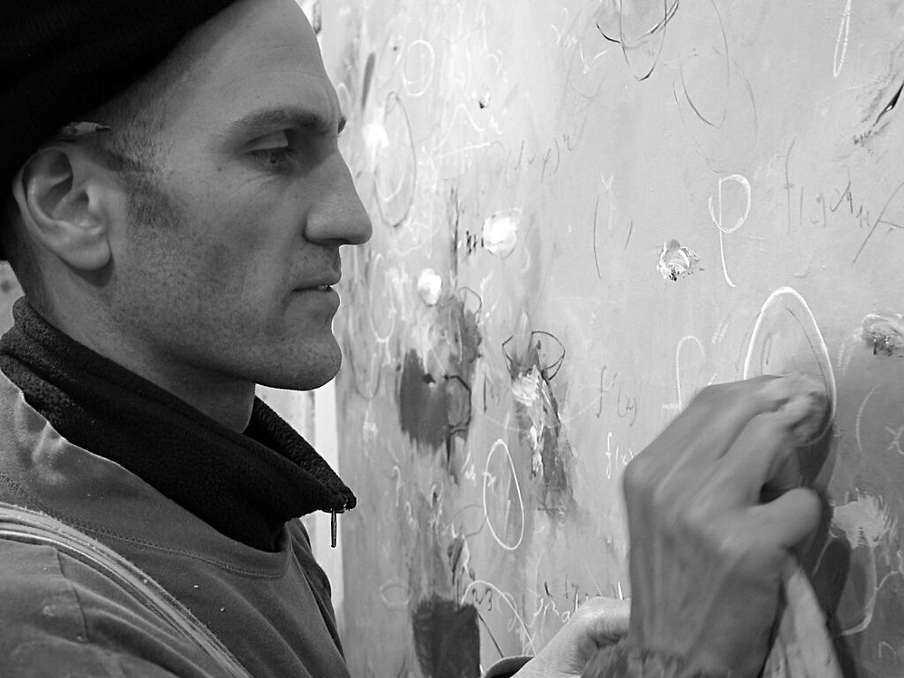 Black and White image of Michael Schultheis writing at a chalkboard