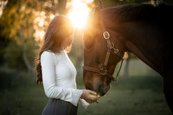 Inniger Moment zwischen Frau und Pferd im goldenen Gegenlicht – sanfte Nähe und Harmonie