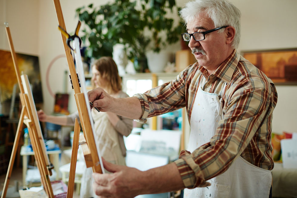 Older man concentrating on painting.
