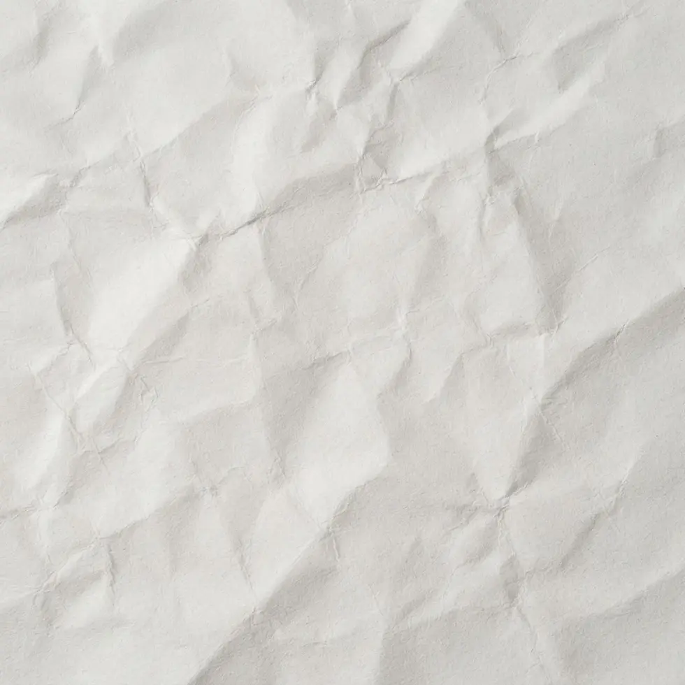 Textural photography of crumpled white paper. The abstract image highlights the tactile quality of the paper's folds and wrinkles.