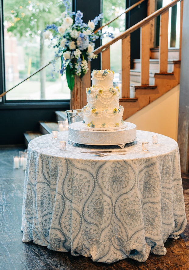 Wedding cake displayed on a patterned linen cake table at 701 Whaley.