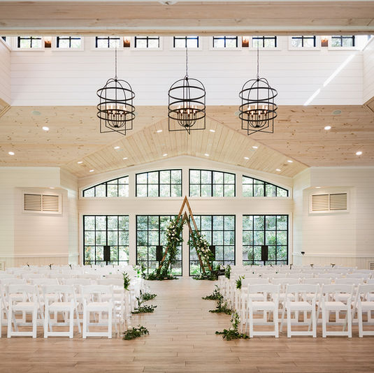 Elegant wedding ceremony setup at The Farm at Old Edwards in Highlands, NC with white chairs, greenery, and wood accents, planned by Eventfully Chic Planning & Coordination.