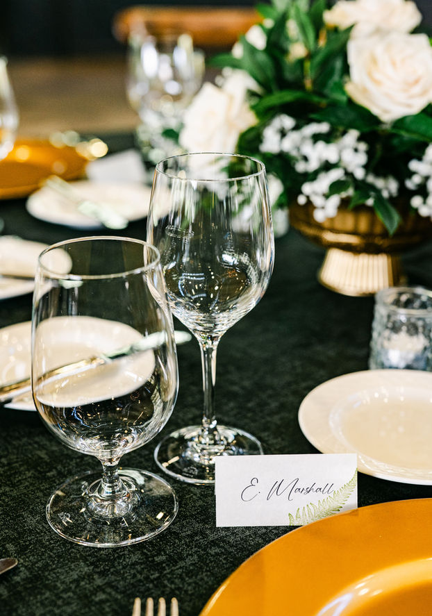 Elegant Old Edwards Inn place setting with gold charger, glassware, floral centerpiece, and handwritten place card.
