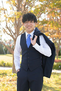 紅葉の中でジャケットを肩に掛けて撮影する成人式のスーツ姿の男性