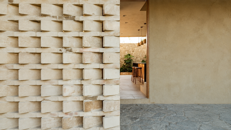 Parede texturizada em arquitetura minimalista com abertura para ambiente interno iluminado por luz natural.