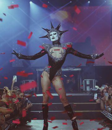 Gotmik from Rupauls Drag Race standing on stage with confetti falling from the air.