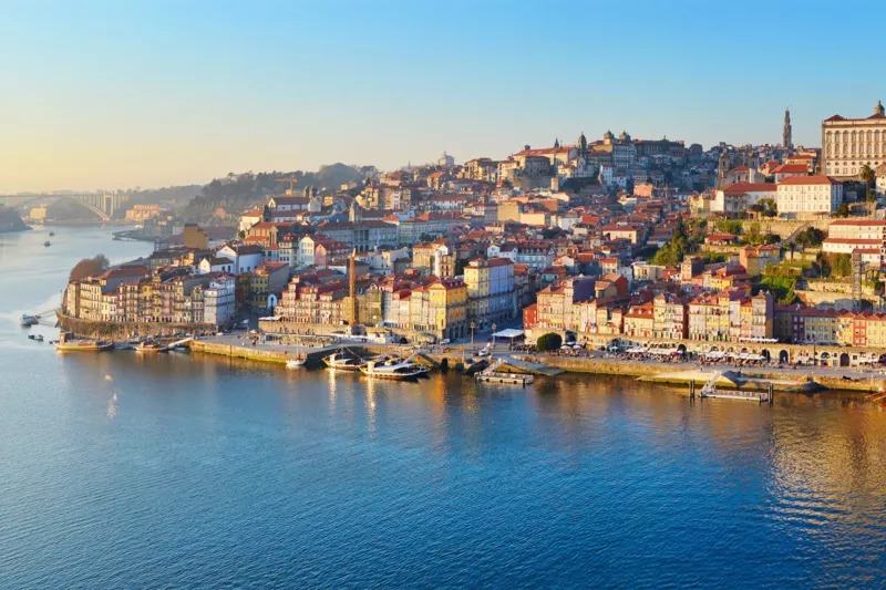 מבני מגורים צבעוניים והיסטוריים לאורך נהר הדואורו ברובע ריביירה בפורטו בשקיעה.