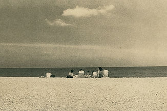 people sitting on a sandy beach. Photograph by Antoni Benavente