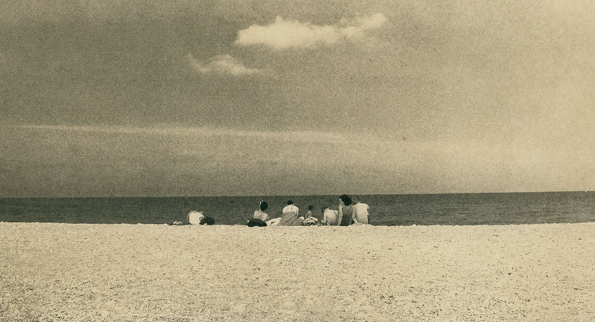 people sitting on a sandy beach. Photograph by Antoni Benavente