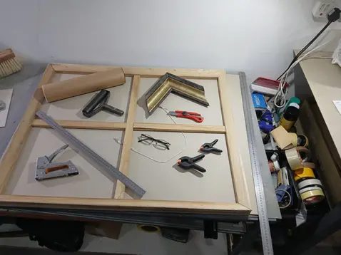 Picture framing tools and wooden frame on a workbench.
