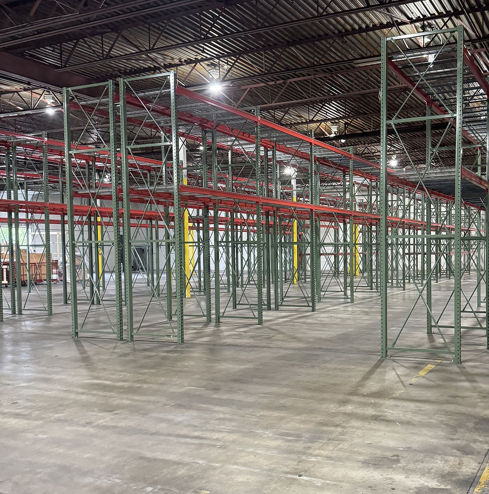 Clean concrete warehouse floor beneath rows of empty red and green pallet racks.