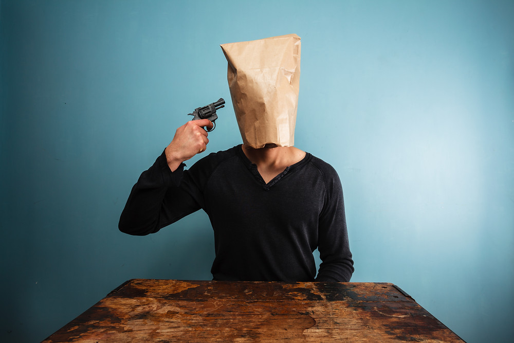 Man with bag over head plays puts revolver to temple.