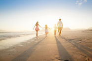 Family Walking On the Beach with the sun in the background
