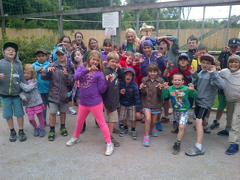 a bunch of children making their hands like claws at a community outing at a zoo