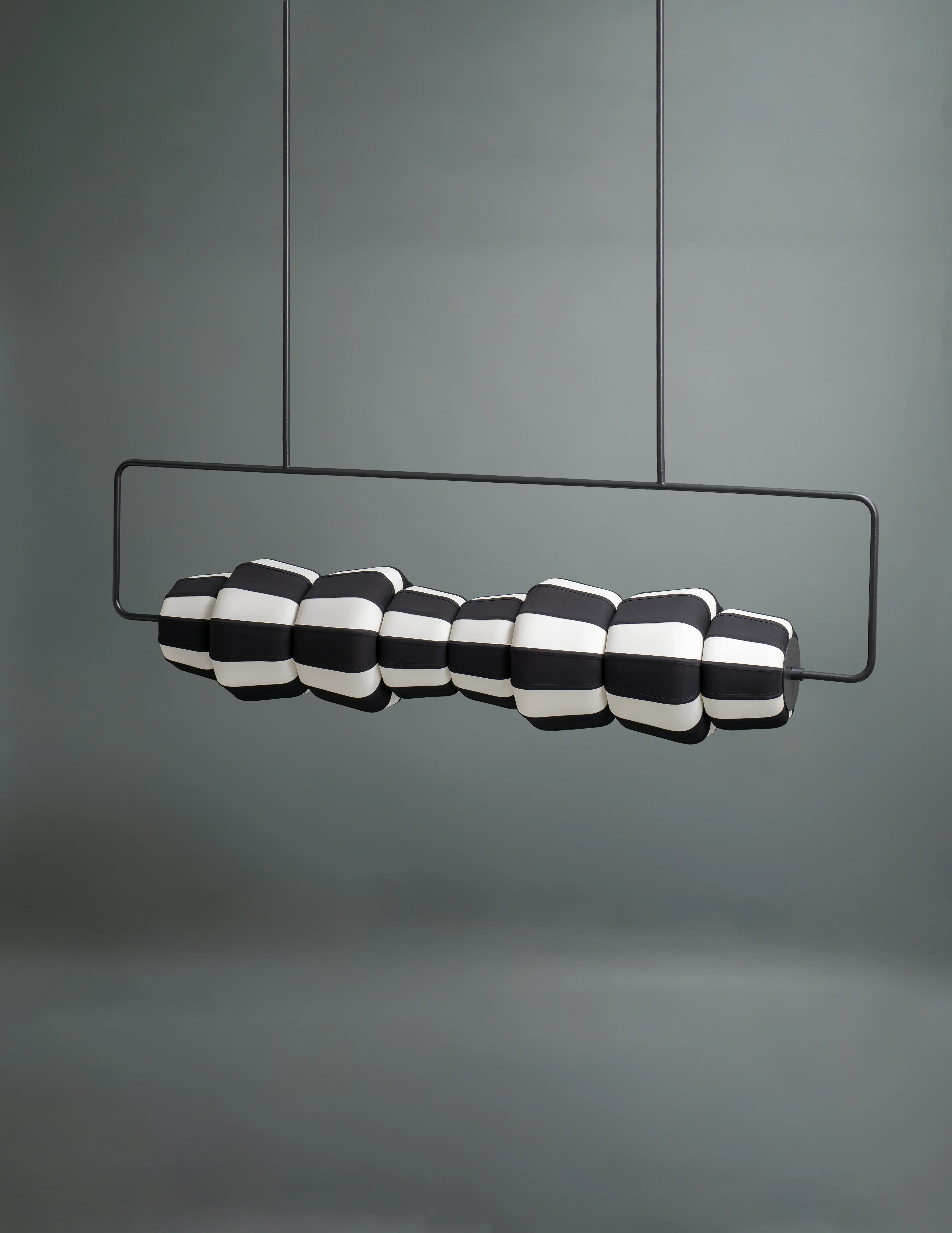 Angled view of the unlit RAYA linear pendant lamp by Name Place Animal Thing, a sculptural light for living rooms.