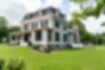 Exterior of beautiful heritage home with a mansard roof and covered porch. Replacement Marvin Ultimate windows with black aluminum clad exteriors throughout the property.