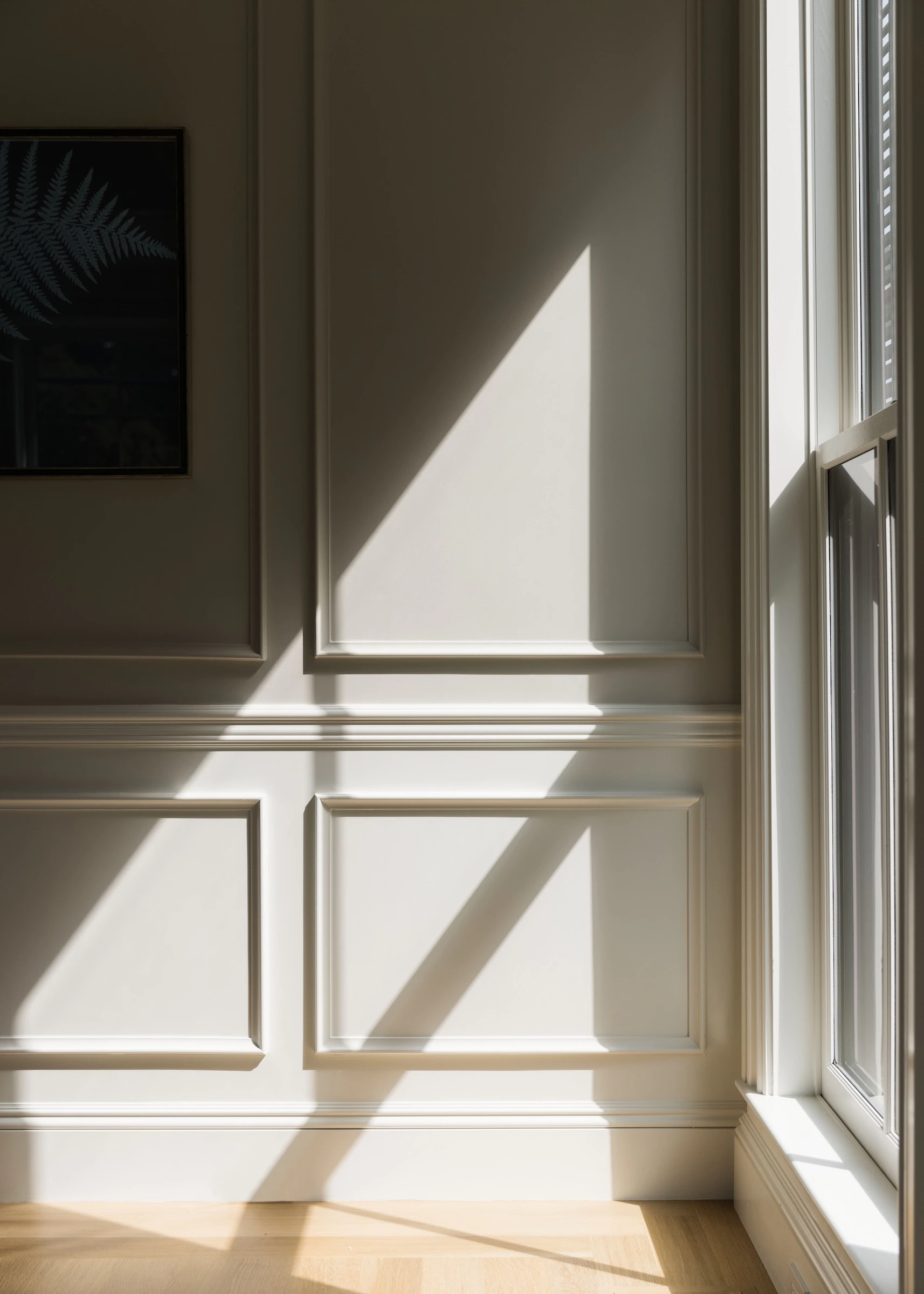Light flows in a replacement Marvin wood window illuminating the historic wainscoting and wood floors