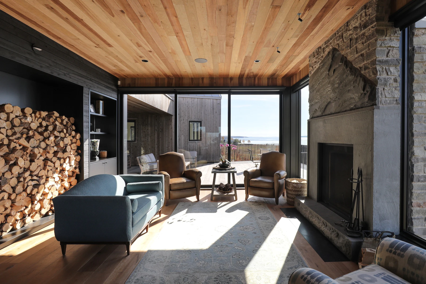 Living room with wood burning fireplace, backed by large Marvin windows
