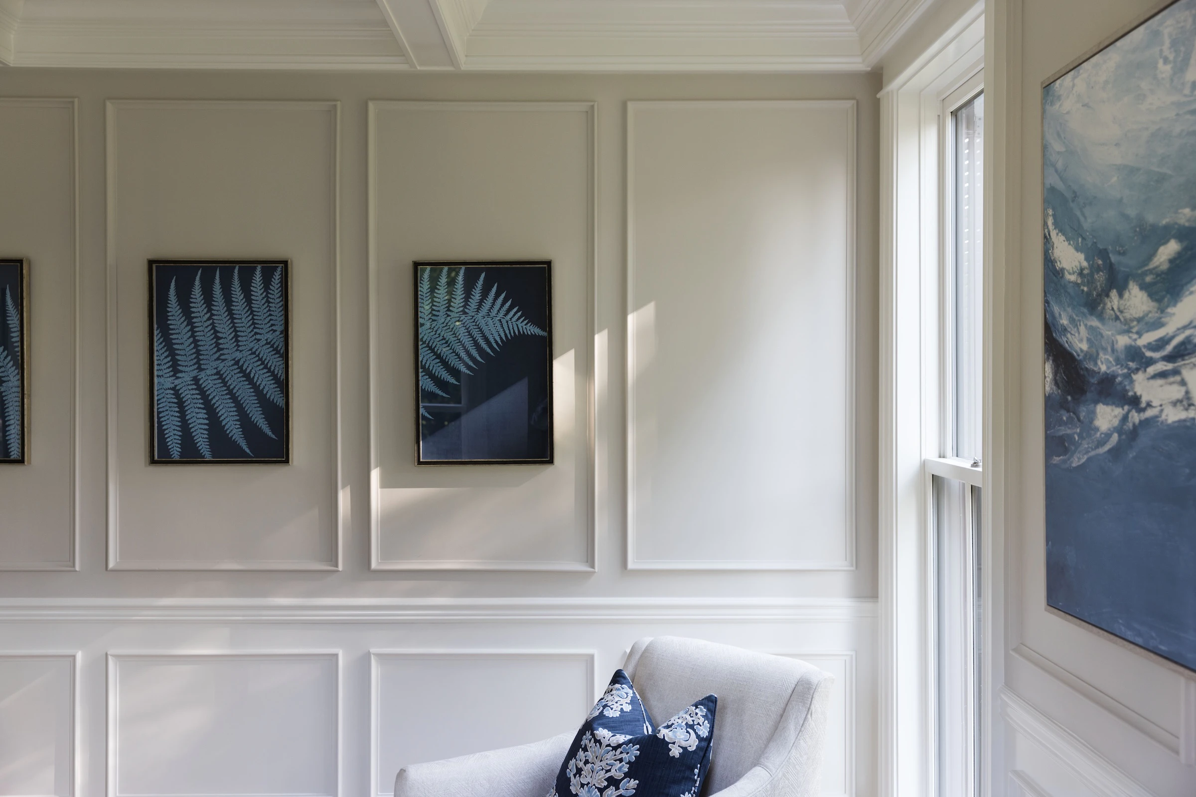 Light flows in a replacement Marvin wood window illuminating the historic wainscoting and wood floors