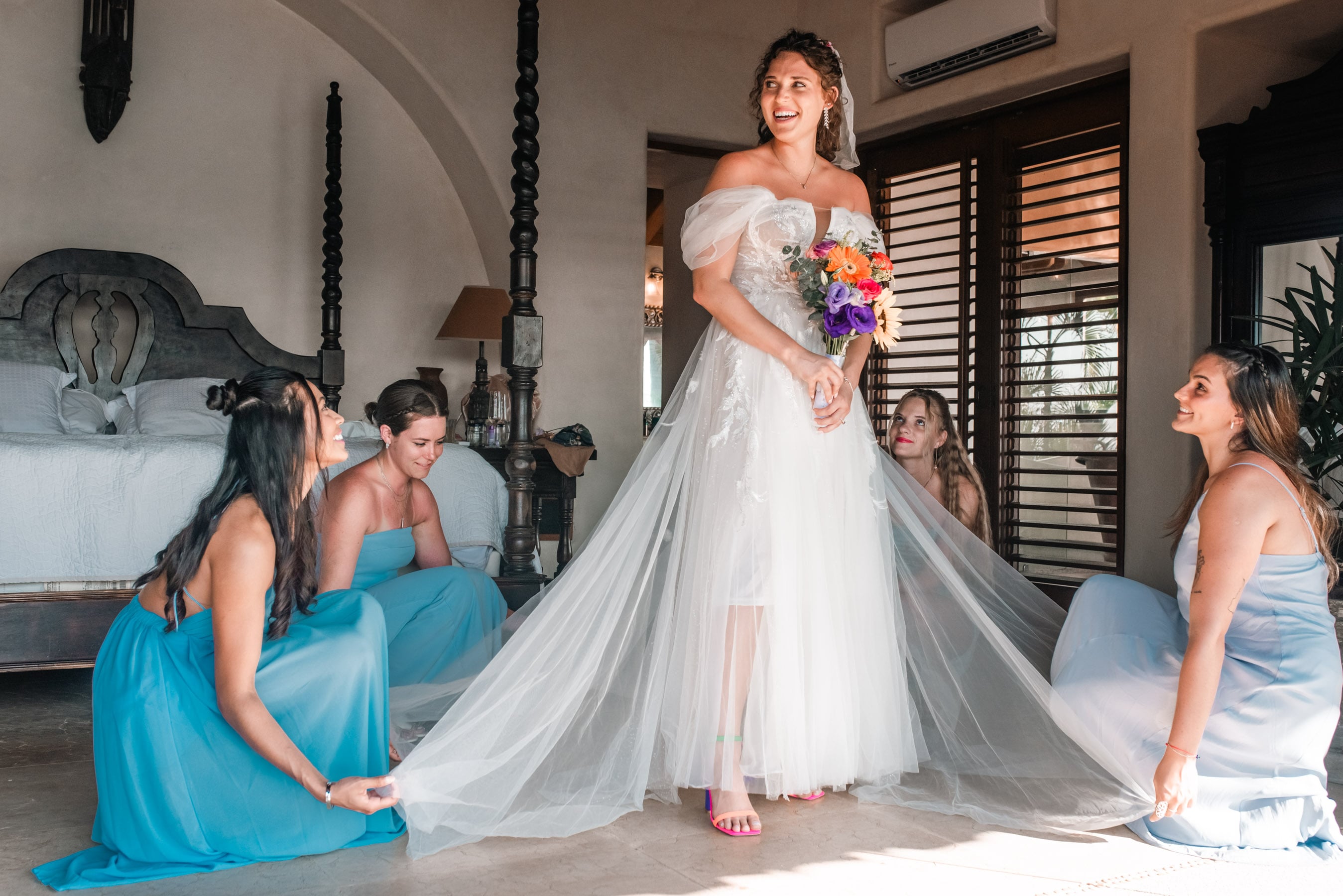 Close-up of the bride's intricate lace gown flowing in the wind, complemented by a bouquet of tropical flowers.
