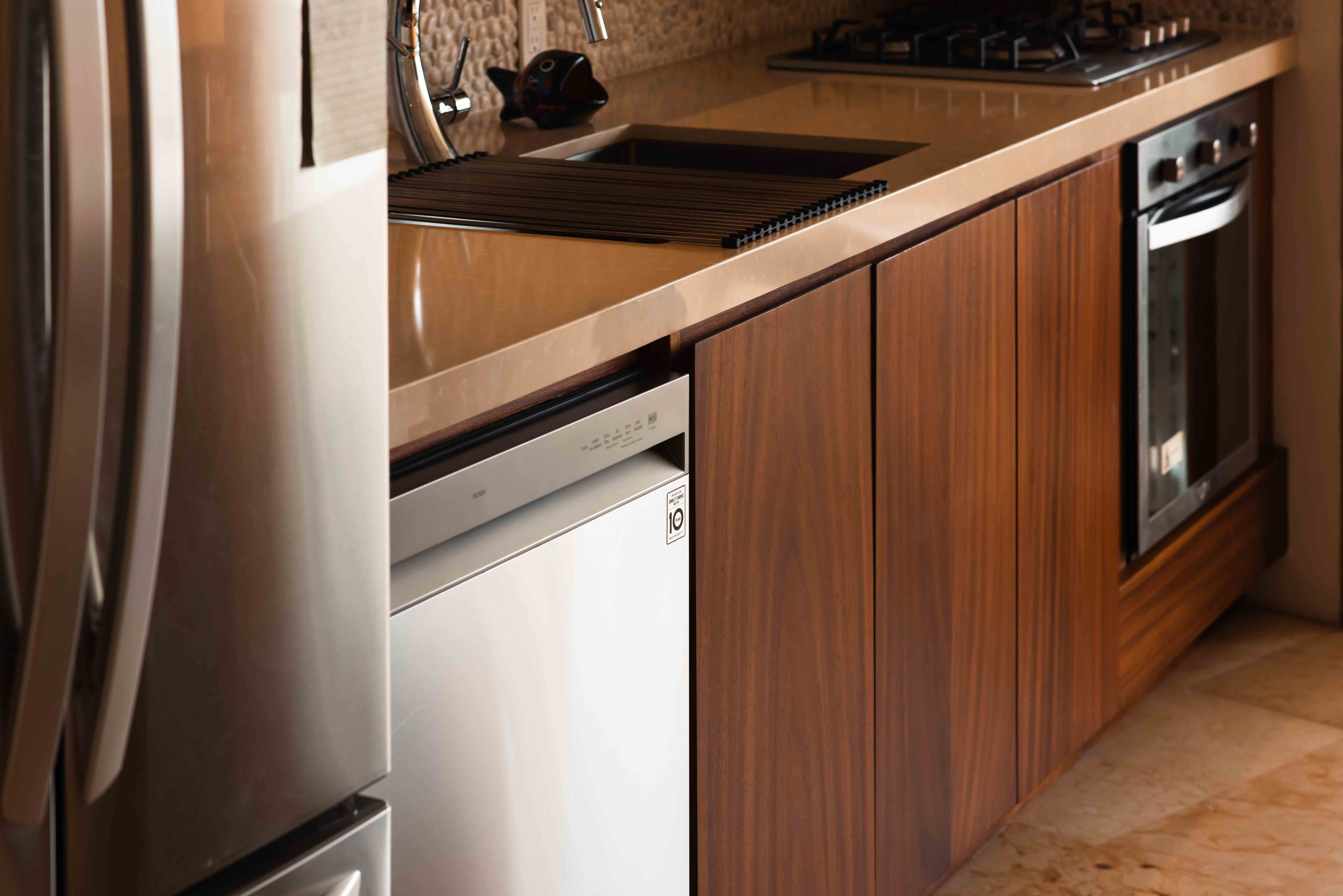 Kitchen detail with wood cabinetry, refrigerator, countertop and wood flooring at Armadillo in Zihuatanejo