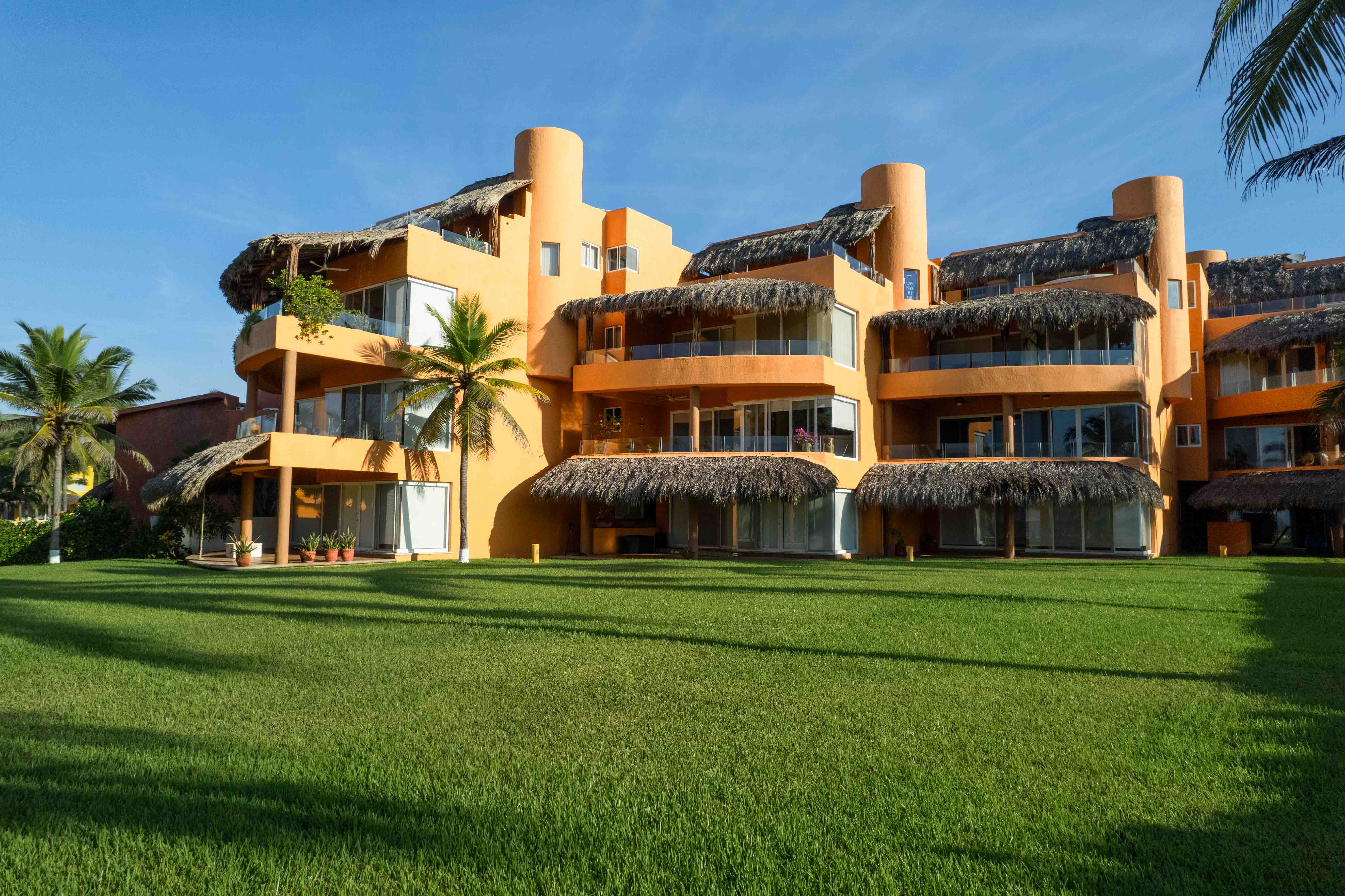 Contemporary condominium surrounded by green lawn with blue sky and modern architecture in Mexico