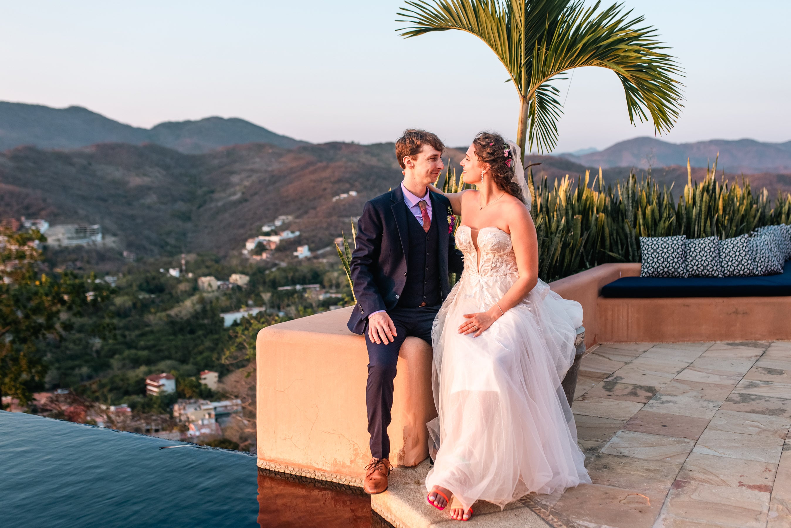 Wedding arch adorned with vibrant tropical blooms, framing the couple as they exchange vows against the ocean backdrop.