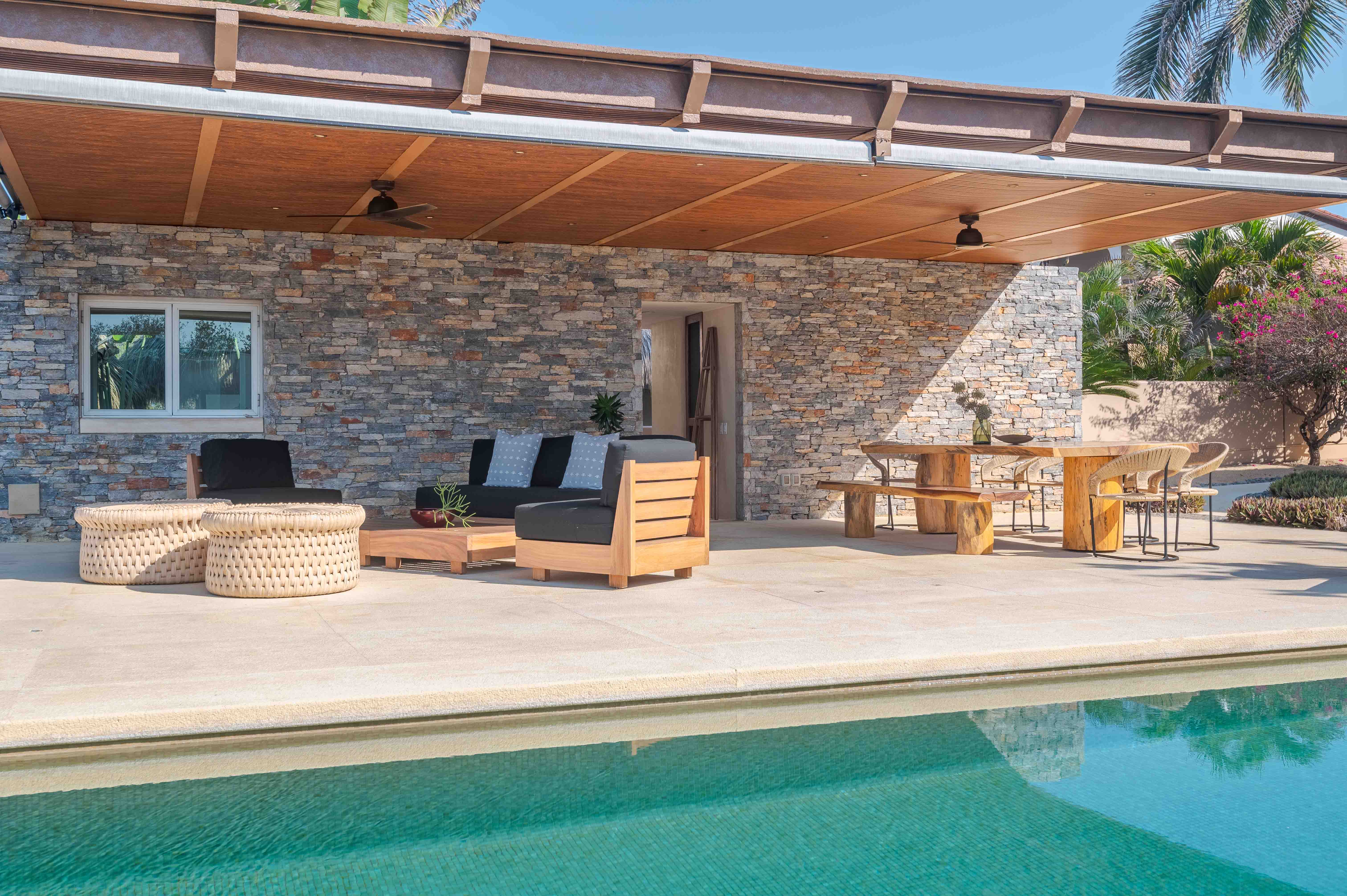Furnished outdoor patio beside a swimming pool in a tropical setting in Mexico