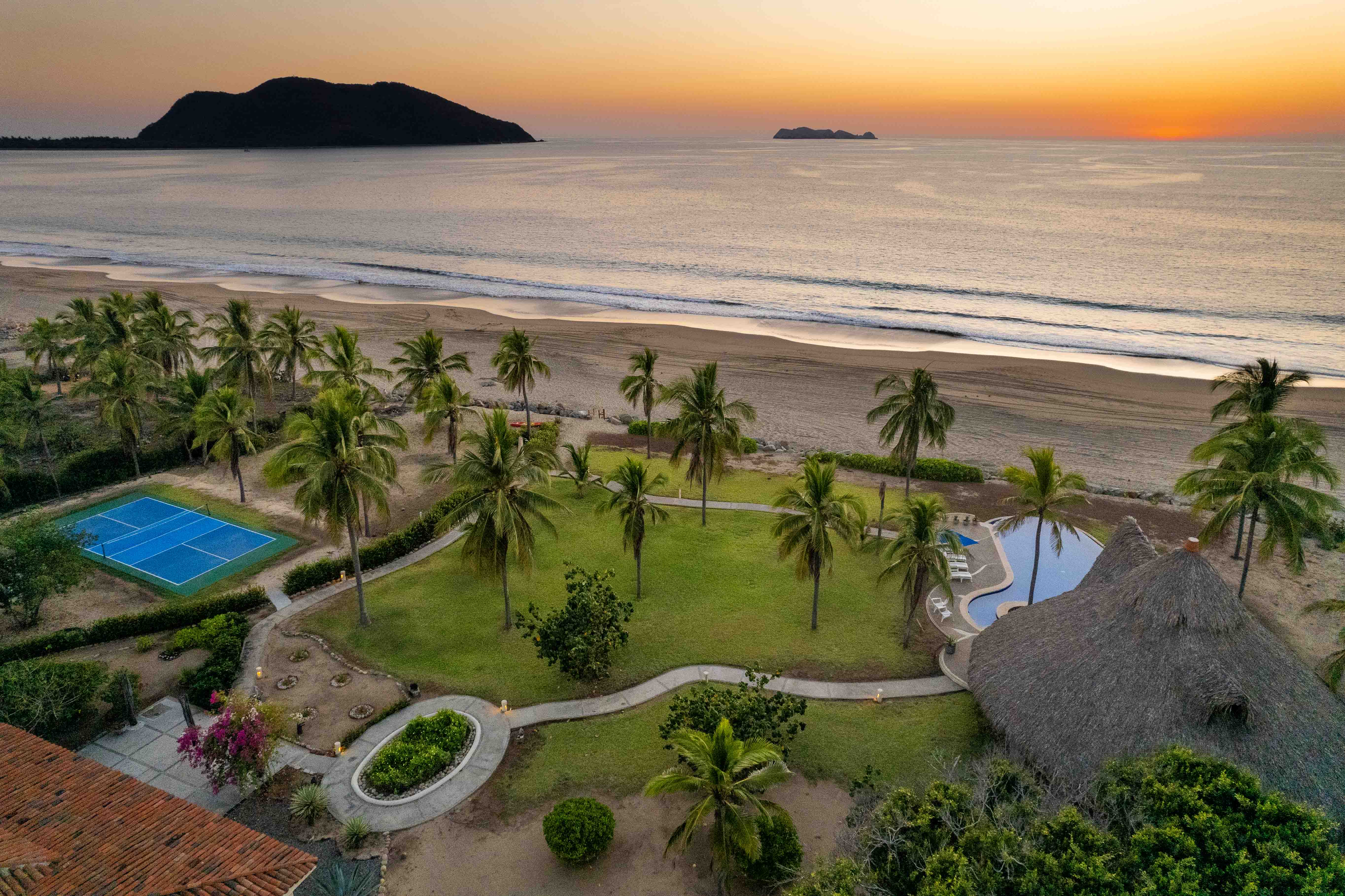 Coastal property with pool, pickleball court and palapa overlooking Barra de Potosí Bay at sunset in Mexico