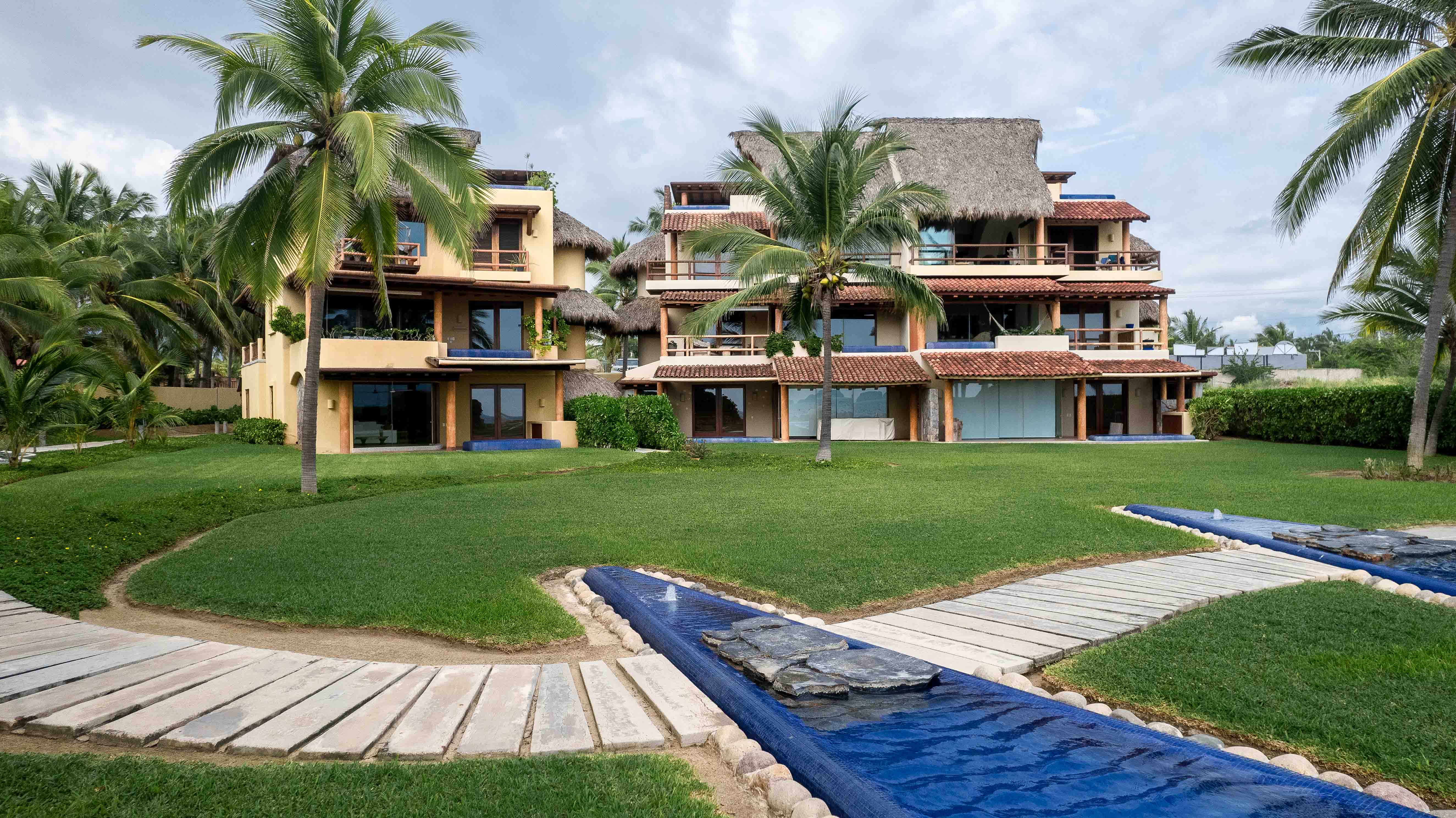 Beachfront condominium with pool, green lawn and coconut palms in Playa Blanca near Ixtapa-Zihuatanejo