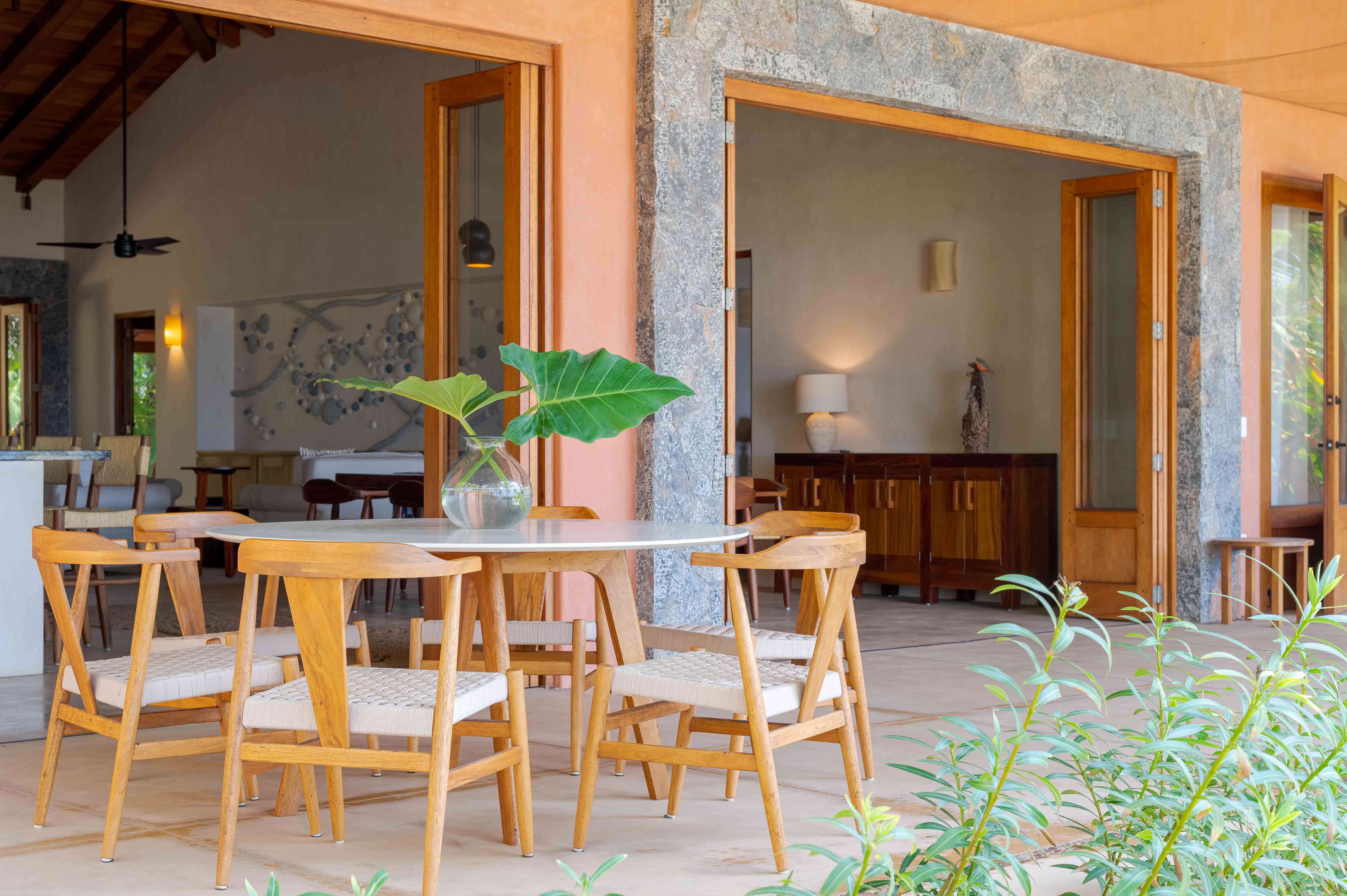 Designer terrace with table and chairs overlooking a living room with stone and wood architecture