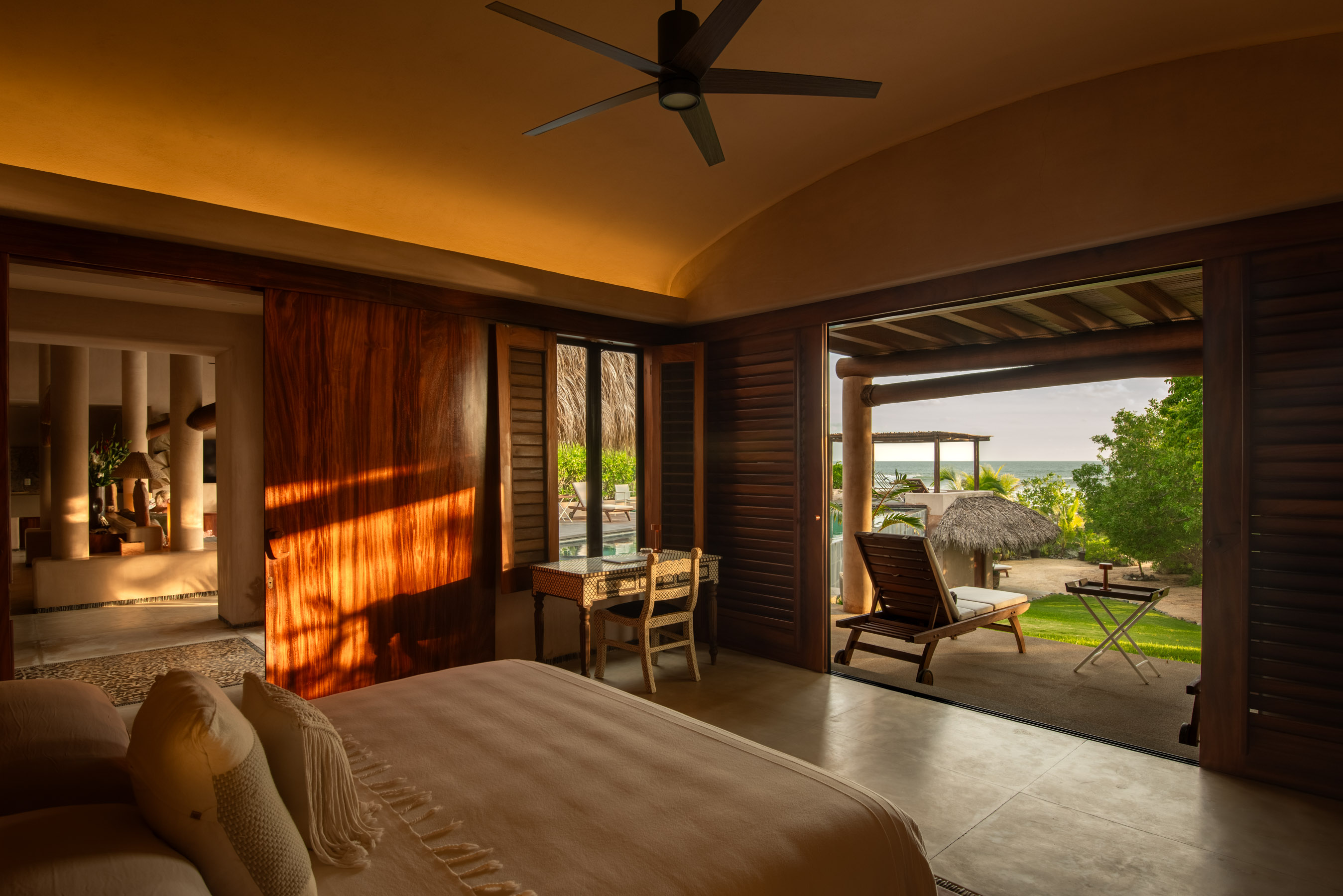 Zozaya bedroom interior with European artwork, sunset light, balcony and ocean view in Mexico
