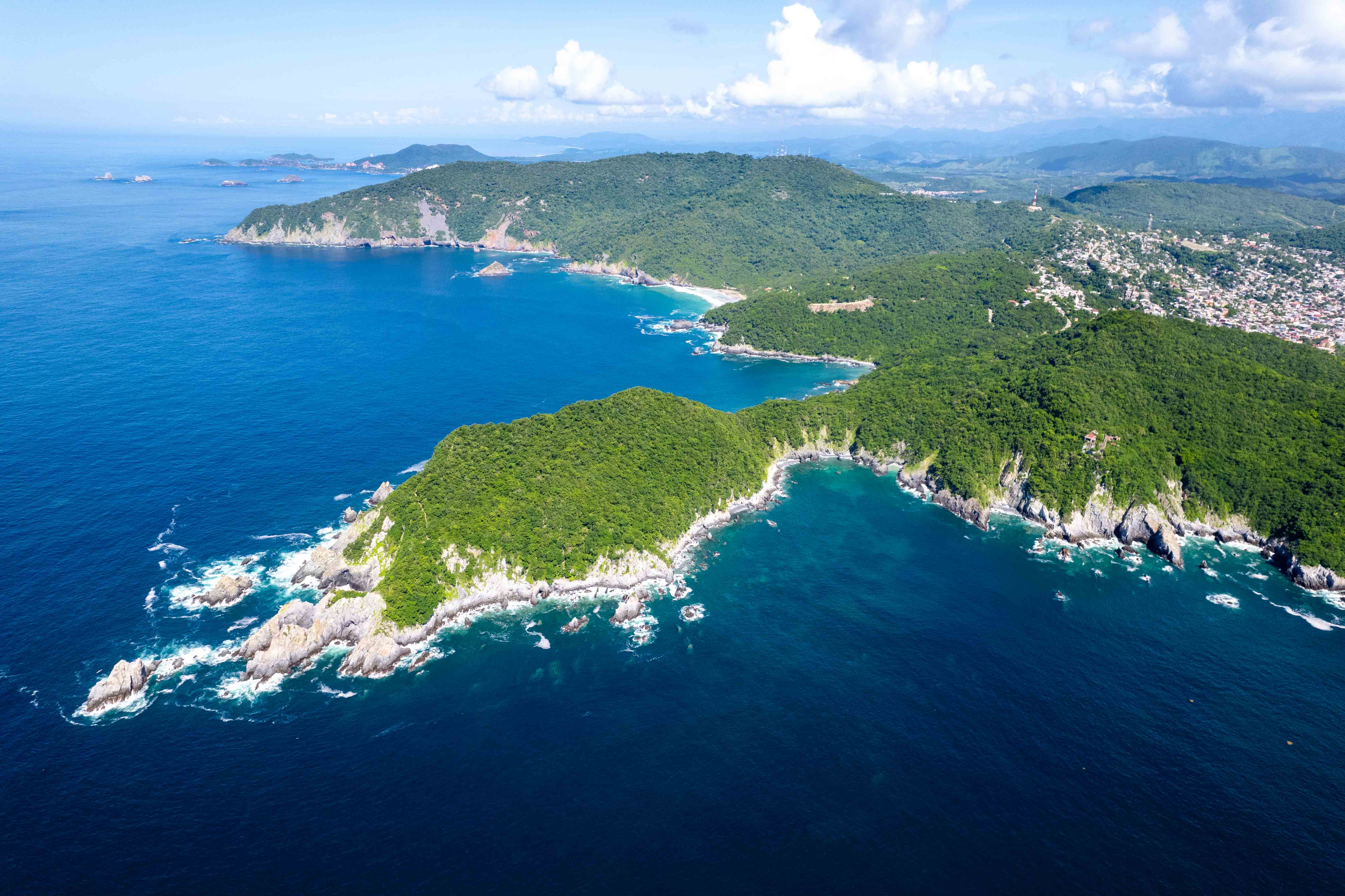 Aerial view of Zihuatanejo Bay with turquoise Pacific Ocean and lush green mountains