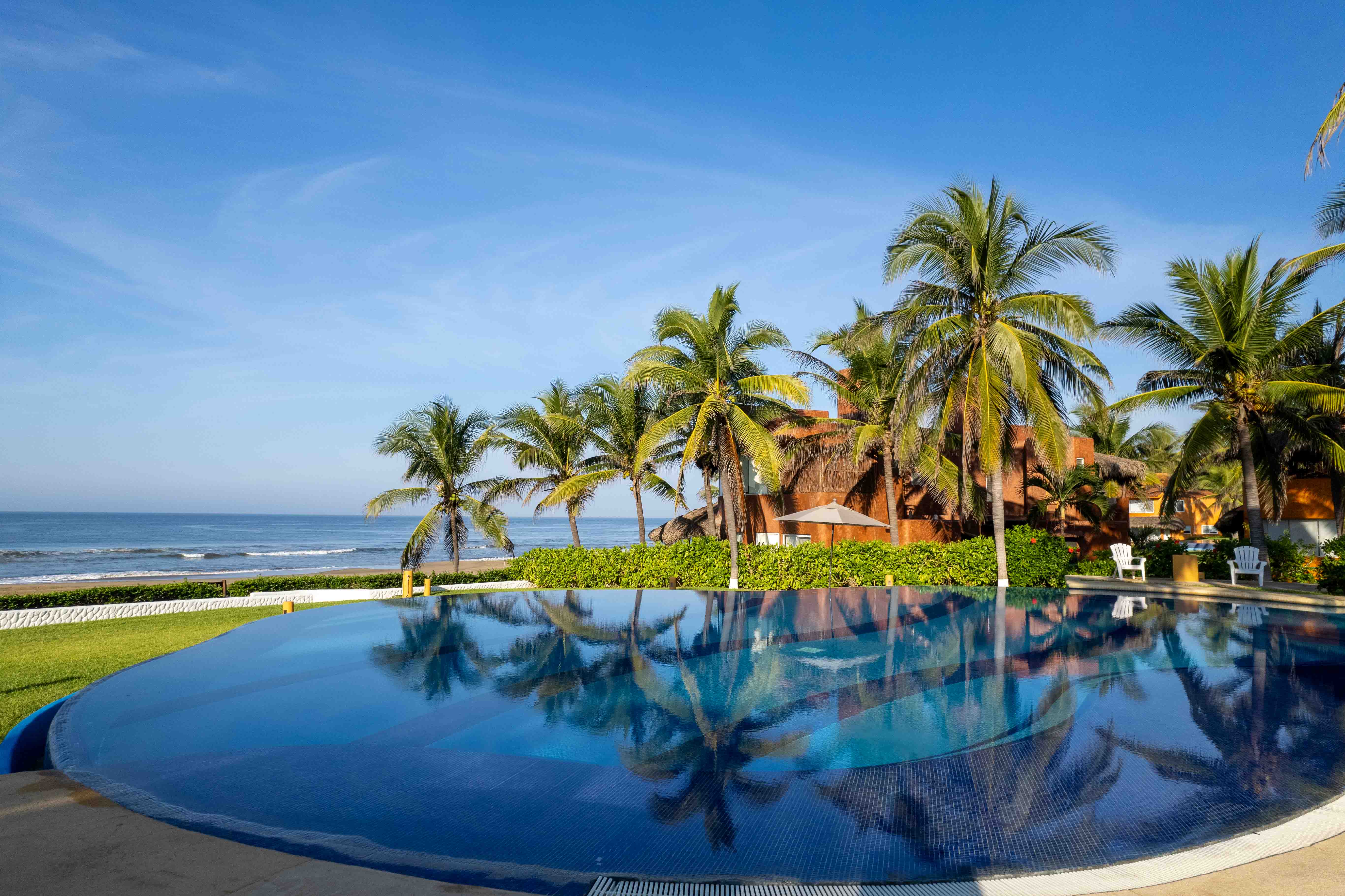 Beachfront hotel pool with palm tree reflections on a clear day along the Pacific coast of Mexico