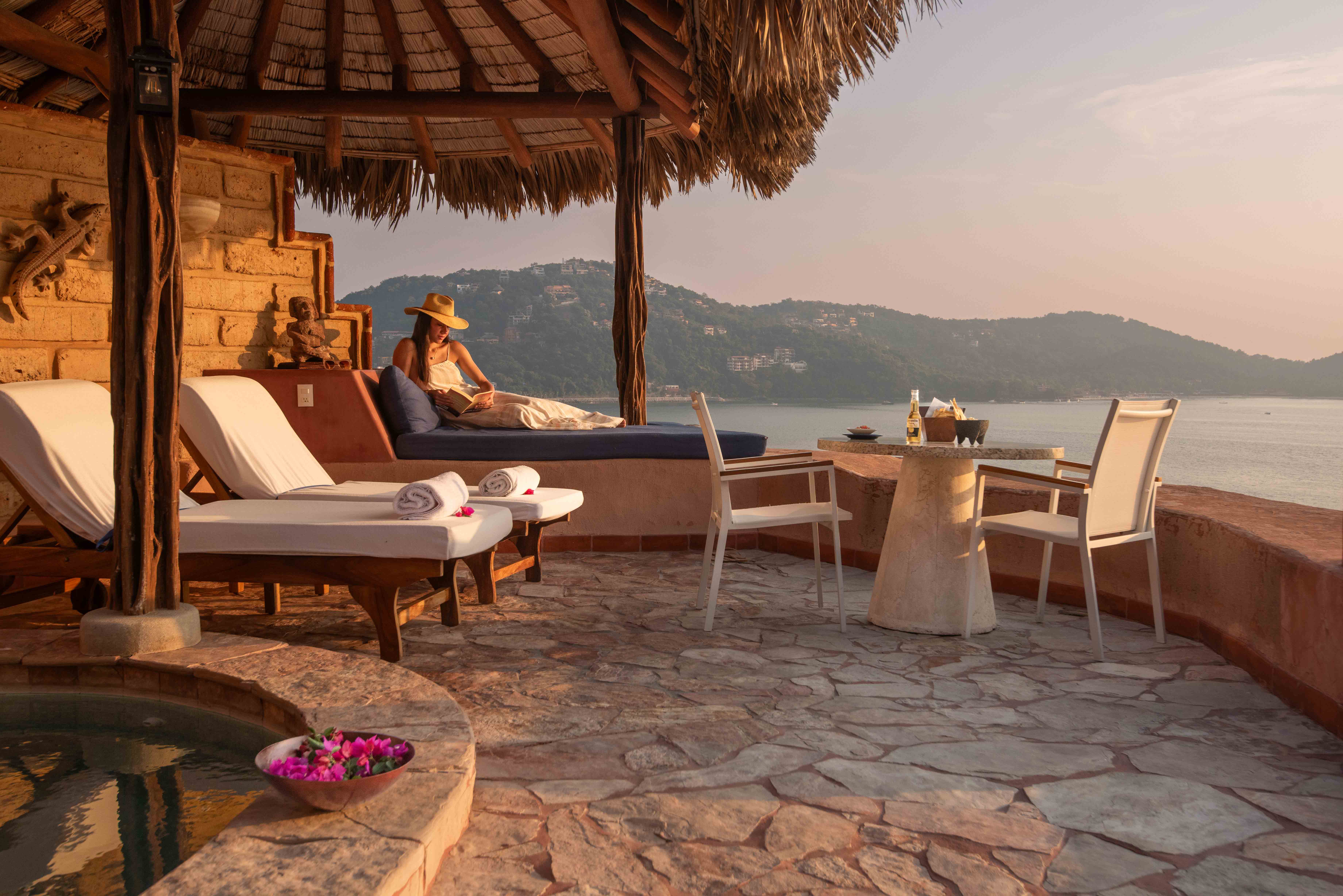 Woman reading on a sofa at the penthouse terrace overlooking La Ropa Bay at La Casa Que Canta