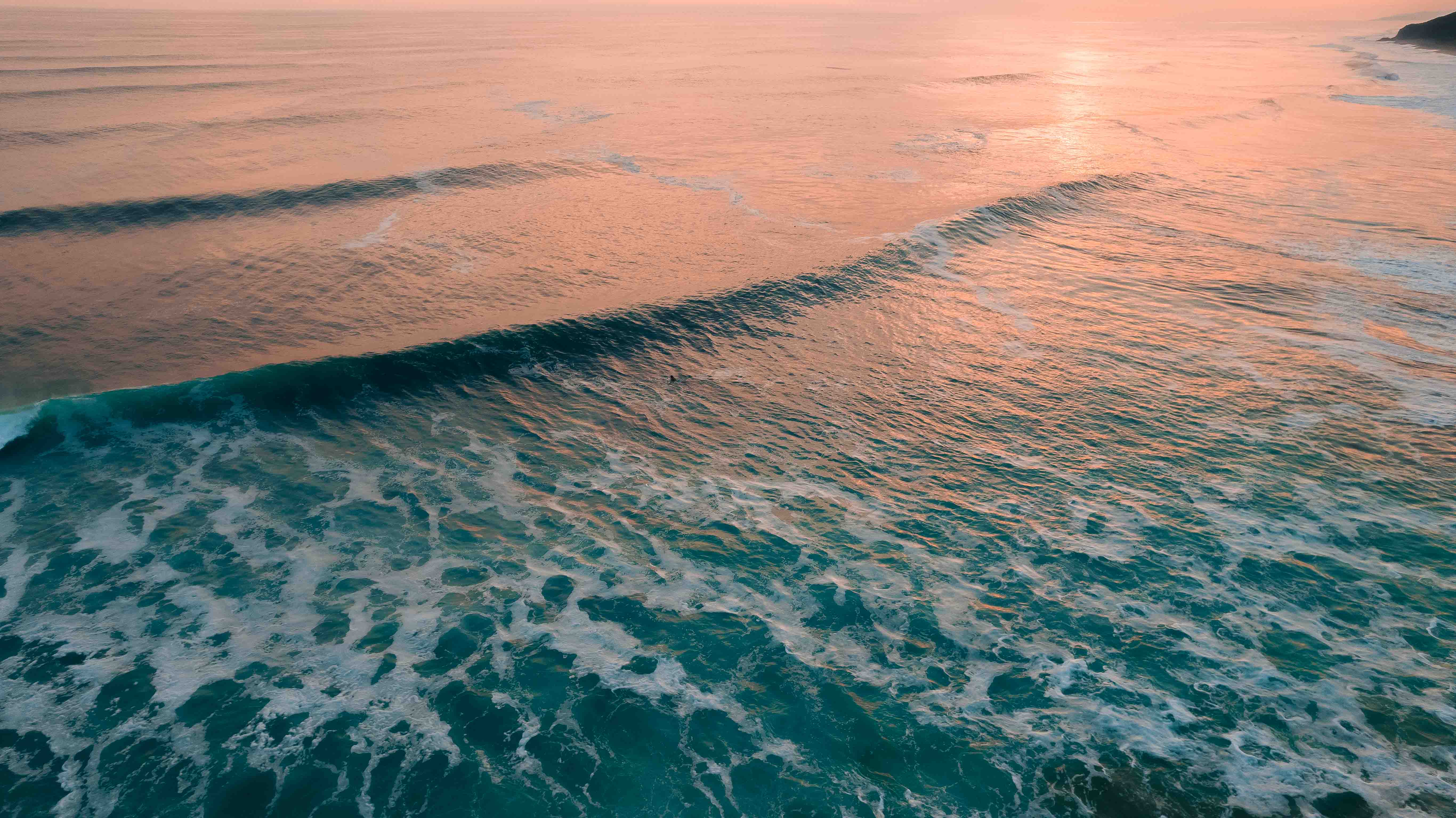 Cinematic aerial view of turquoise and golden ocean waves at sunset along the Pacific coast of Mexico